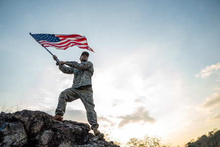 Hand Waving the Flag of the United States of America in memorial day . Us soldier holding American flag celebrating.US Army soldier celebrates holding USA flag celebrating Independence USA dayの写真素材