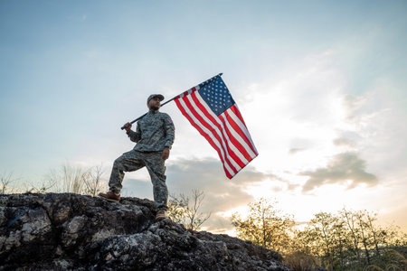 Hand Waving the Flag of the United States of America in memorial day . Us soldier holding American flag celebrating.US Army soldier celebrates holding USA flag celebrating Independence USA dayの写真素材
