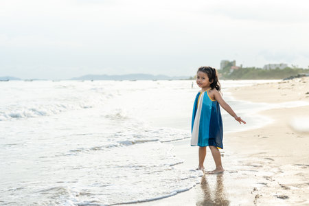 Cheerful adorable little girl having fun outdoor and playing with sand with beach kid toys on the beach in the summer vacation at sunset, happy healthy toddler playful on the tropical seaside.の写真素材