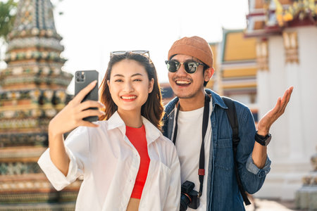 Young Asian couple man and woman traveling backpacker walking in temple at Bangkok Thailand. Happy...