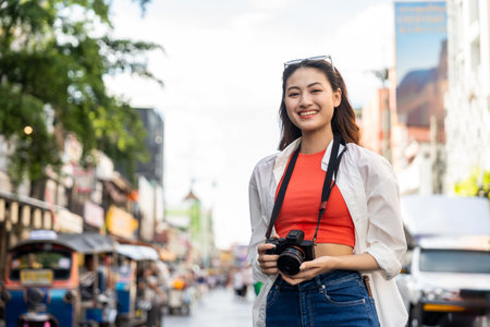 Young Asian woman traveling backpacker in Khaosan Road outdoor market in Bangkok Thailand. Happy female tourist walking in the downtown street traditional marketの写真素材