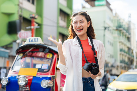 Young Asian woman traveling backpacker in Khaosan Road outdoor market in Bangkok Thailand. Happy female tourist walking in the downtown street traditional marketの写真素材