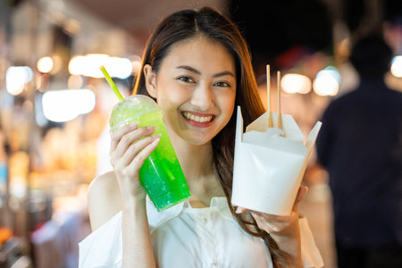 Asian woman enjoy eating noodles street food at night market. Traveler Asian blogger women Happy tourists Beautiful female with Traditional thailand bangkok food.の写真素材