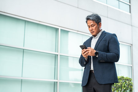 Senior manager business man in suit with cell phone at the buildings downtown. Confident man using smartphone looking towards their goals for success. Executive business manの写真素材