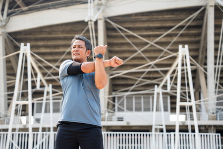 Senior old asian man wearing sportswear warming up before running outdoor. Portraits of Mature man stretching body before running at sport stadium. Training athlete work out at outdoorの写真素材