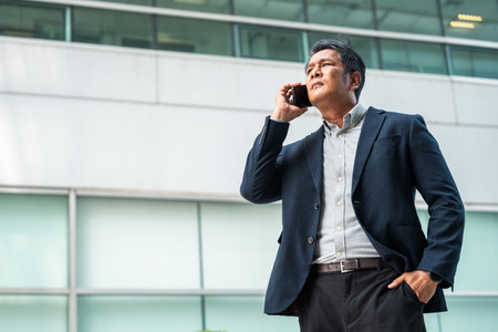 Senior manager business man in suit with cell phone at the buildings downtown. Confident man using smartphone looking towards their goals for success. Executive business manの写真素材