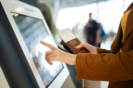 Close up the woman hands touching the screen while self check in kiosk technology machine getting boarding pass at the airport terminalの写真素材