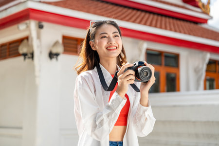 Young Asian woman traveling backpacker walking in temple at Bangkok Thailand. Happy female tourist walking in the downtown street traditional ancient temple. Holiday vacation time touristの写真素材