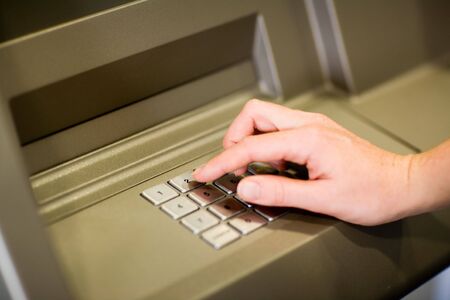Entering number at ATMの写真素材