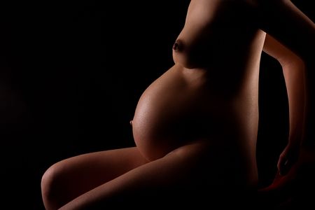 Pregnant woman (8th month). Art-Shot, black background. Light and shadows.の写真素材