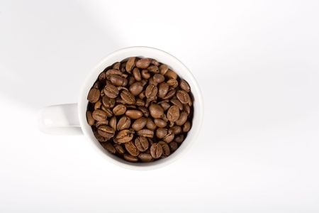 White mug, filled with coffeebeans on white background. Top view.の写真素材