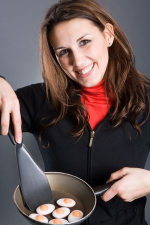 A beautiful woman frying eggs in a pan. Eggs are made of sugar.の写真素材