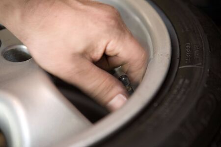 A closeup view of a hand touching the valve stem of an auto tireの写真素材