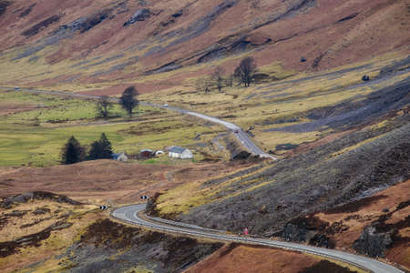 A road passing through a mountain valley of Scottish Highlands and a white house. Glen Coe, Scotlandの写真素材