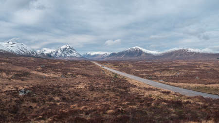 Panorama of a road leading through the Scottish Highlands of Glen Coe, snowcapped mountains and valley. Scotlandの写真素材