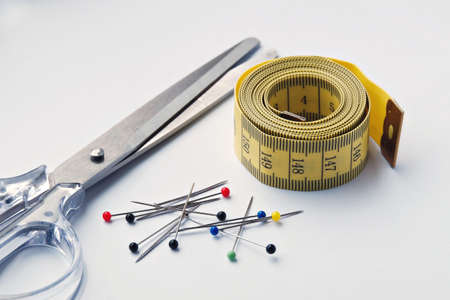 Set for needlework with cissors, measure tape and colored pins isolated on white.
