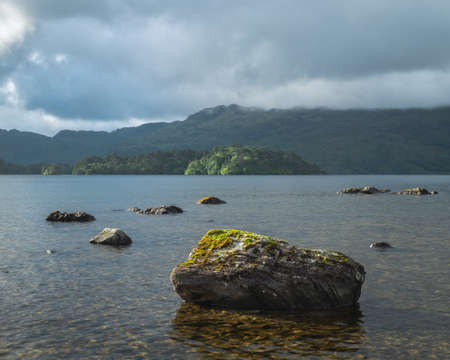 A view of Scotlands Loch Morar with a big foreground stone in the water. Taken low on the shoreline.の写真素材
