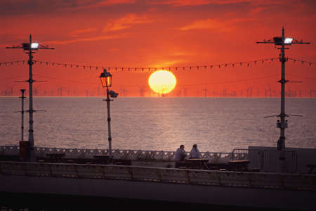 Silhouette of two girls relaxing on pier against the setting sun. Blackpool, United Kingdomの写真素材