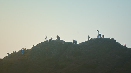 People watching cityscape in the top of hill. Arthurs Seat, Edinburgh, Scotland, United Kingdomの写真素材