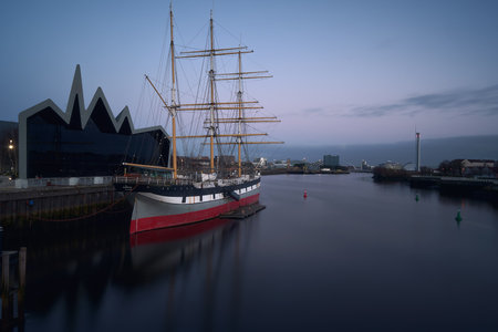 Old sailing ship moored to the pier on the River Clyde in the evening. Glenlee, steel-hulled three-masted barque. The Tall Ship at Glasgow Harbourの写真素材