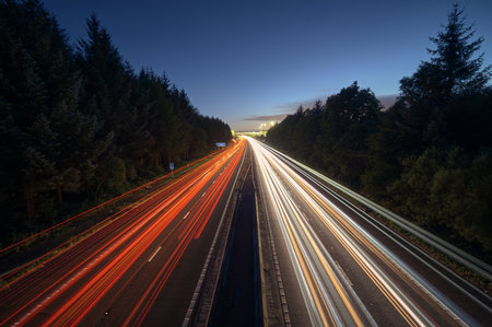 Long exposure photo of highway at night with colorful light trails from cars. Concept of traffic,...