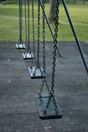 Empty swings gently hanging in a quiet park on a calm day. Peaceful and nostalgic atmosphere. Linlithgow, Scotlandの写真素材