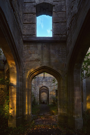 Interior view of Dunmore House ruins in Scotland. Arched stone doorways and soft evening light illuminating ancient walls with plants growing inside the abandoned building.の写真素材