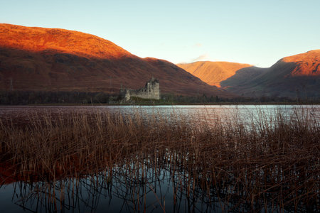 Scottish ruins of an ancient castle on an autumn morning. Autumn colours on the hills illuminated by the morning sun behind. Loch Awe, Argyll and Bute, Scotland, UKの写真素材