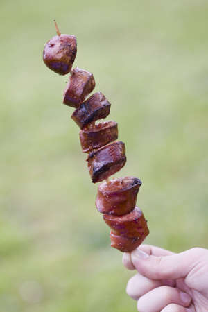 closeup on grilled sliced sausage on a stickの写真素材