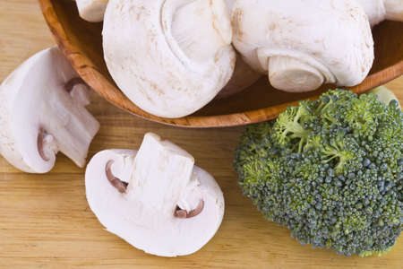 Fresh mushrooms and broccoli in the wooden cutting boardの写真素材