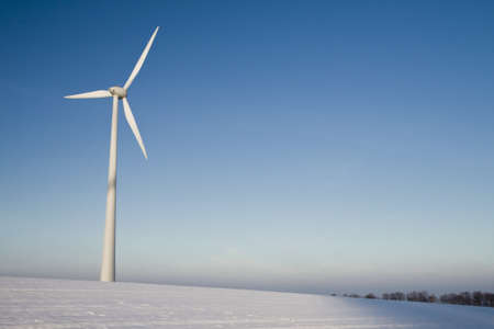 Windmill on a blue sky in winter, alternative energy sourceの写真素材