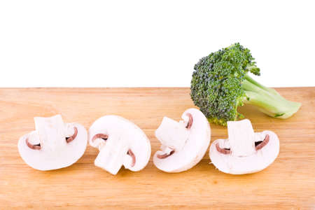 Fresh mushrooms and broccoli on the wooden cutting boardの写真素材