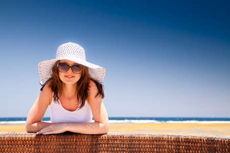 The young beautiful girl in a hat on vacation, on a sunny beachの写真素材