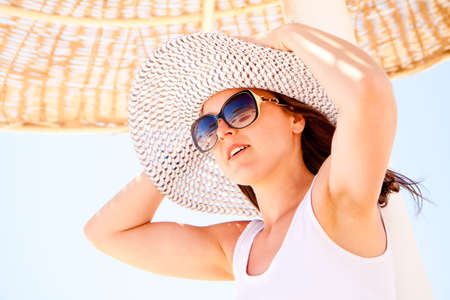 A young pretty woman holding her hat on the beachの写真素材
