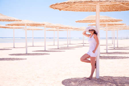 Young girl standing under an umbrella on the beachの写真素材