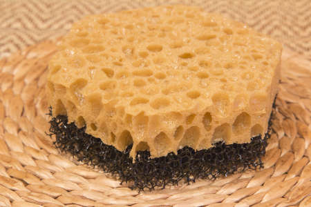 Sponge for washing dishes on a straw background.