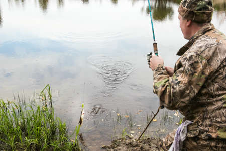 A fisherman on the river catching pike on spinning
