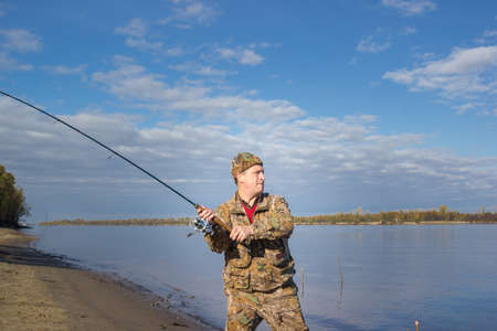 The man swung throws a spinning lure in the river