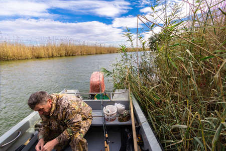 Fisherman sitting in the boat and prepare for the upcoming fishing tackleの写真素材