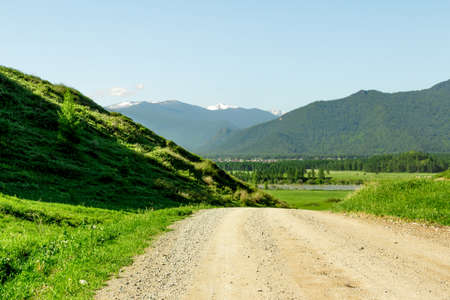 Country dirt road passes near the mountainsの写真素材