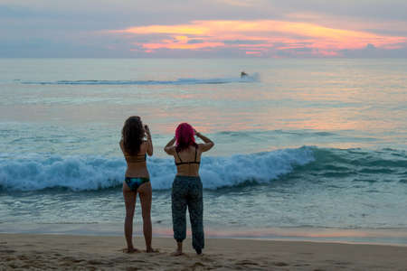 Two girls on the beach of Karon in Phuket meet sunsetの写真素材
