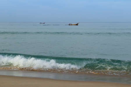 Men on a long wooden fishing boat Thailandの写真素材