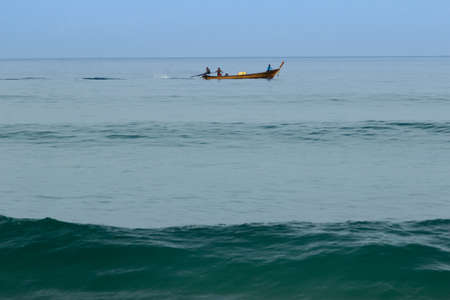 Men on a long wooden fishing boat Thailandの写真素材