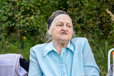 Emotional portrait of my grandmother Valya in the nature on a country cottageの写真素材