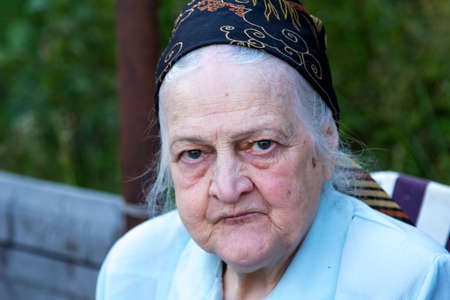 Emotional portrait of my grandmother Valya in the nature on a country cottageの写真素材