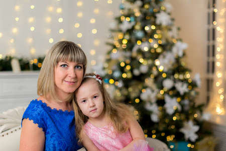 Mom and daughter on the background of a decorated Christmas treeの写真素材