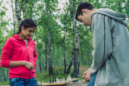 Girl and boy playing chess on the nature.の写真素材