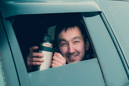 A young man looks out of an open window of an SUV carの写真素材