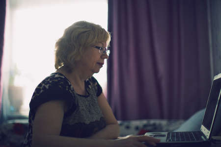 An elderly woman enthusiastically working at the computerの写真素材