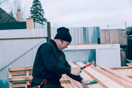 A man hammers a nail into a wooden boardの写真素材